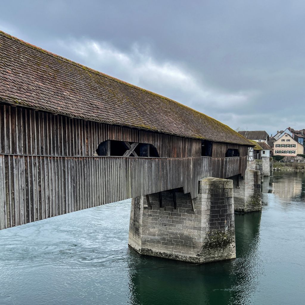 Wir wandern an einer Holzbrücke vorbei, die nach Deutschland führt.