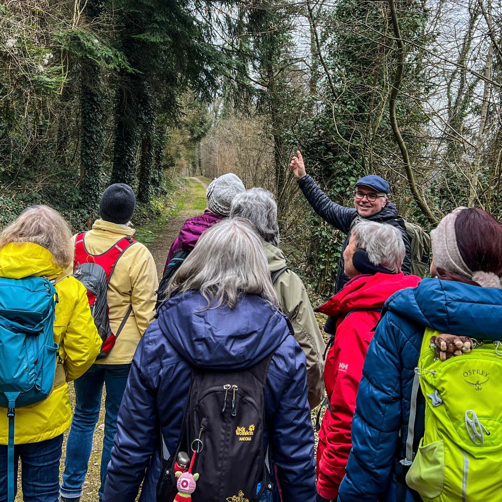 Der Wanderleiter erklärt den Seniorinnen etwas über Bäume und Pflanzen.