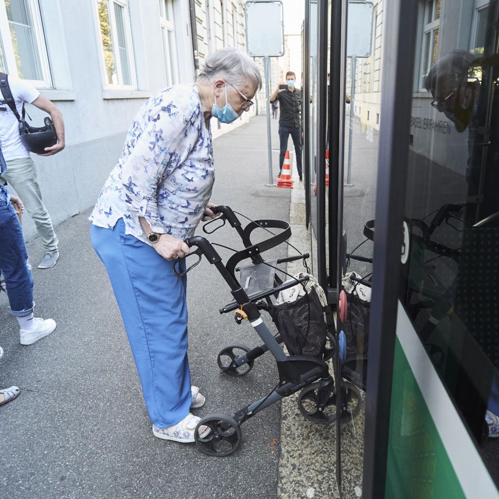 Seniorin steigt selbstständig mit ihrem Rollator in einen Bus ein.