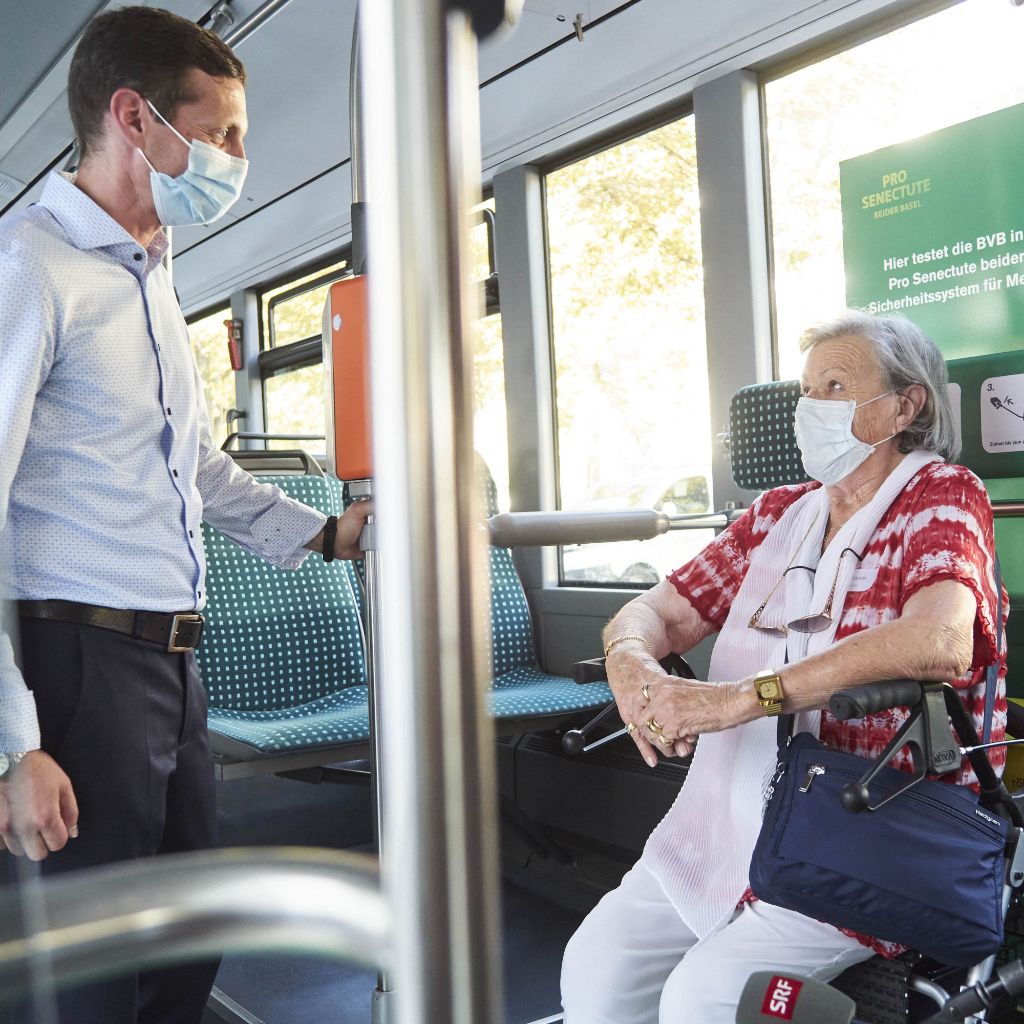 Mitarbeiter unterhält sich im Bus mit Seniorin, die auf ihrem Rollator sitzt.