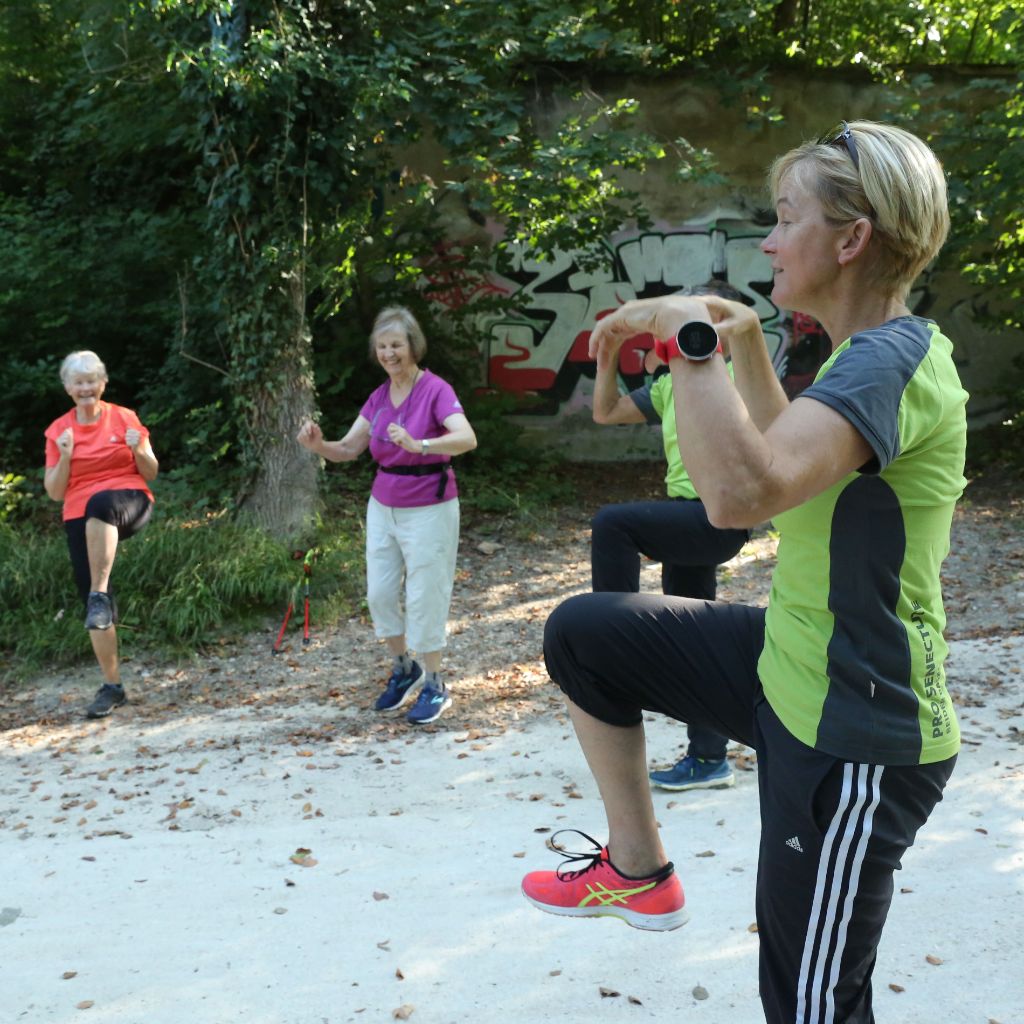 Seniorinnen befolgen beim Nordic Walking die Anweisungen ihrer zwei Kursleiterinnen.