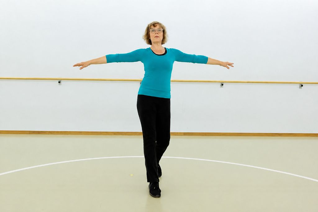Tanzlehrerin zeigt in Turnhalle Tanzschritte vor.