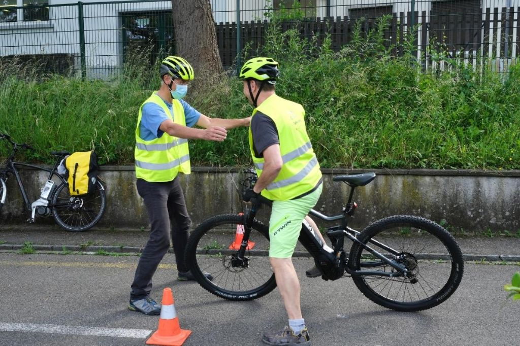 Ein Kursleiter eines E-Bike-Kurses hilft einem Teilnehmer bei den ersten Schritten.