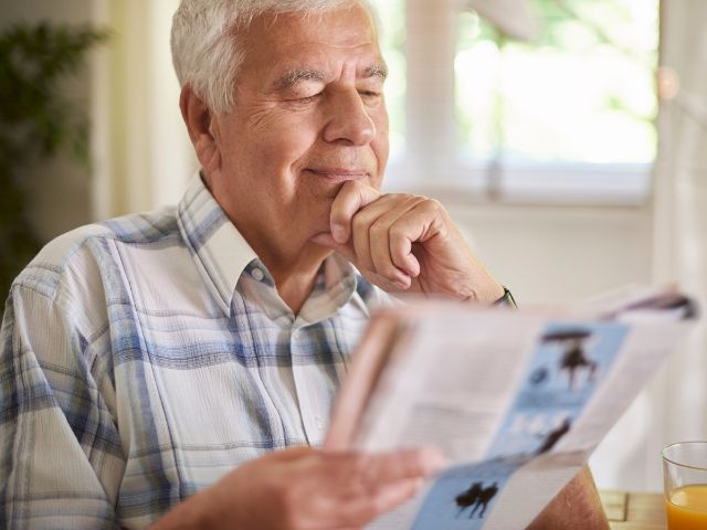 Senior liest in ruhiger Umgebung eine Ausgabe vom Akzent Magazin.