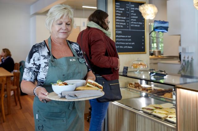 Eine Mitarbeiterin von Café Nona trägt feines Menü zum Gast.