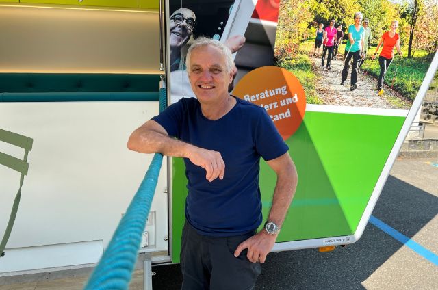 Ein Infobus-Fahrer steht lächelnd vor dem Bus.