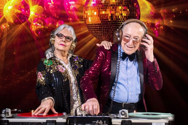Eine Seniorin und ein Senior machen Party unter einer Discokugel.