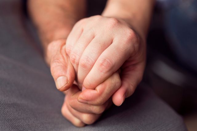 Eine ältere und eine jüngere Person halten sich an den Händen.