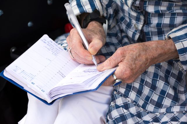 Seniorin notiert sich Termin in ihre Agenda.