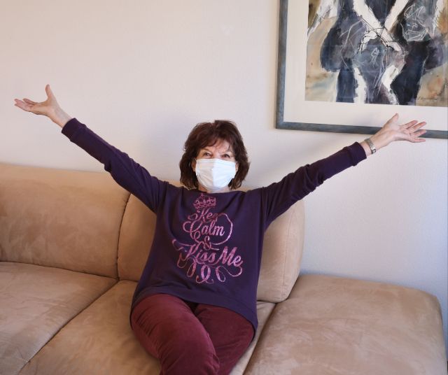 Glückliche Seniorin sitzt nach Umzug auf ihrem Sofa.