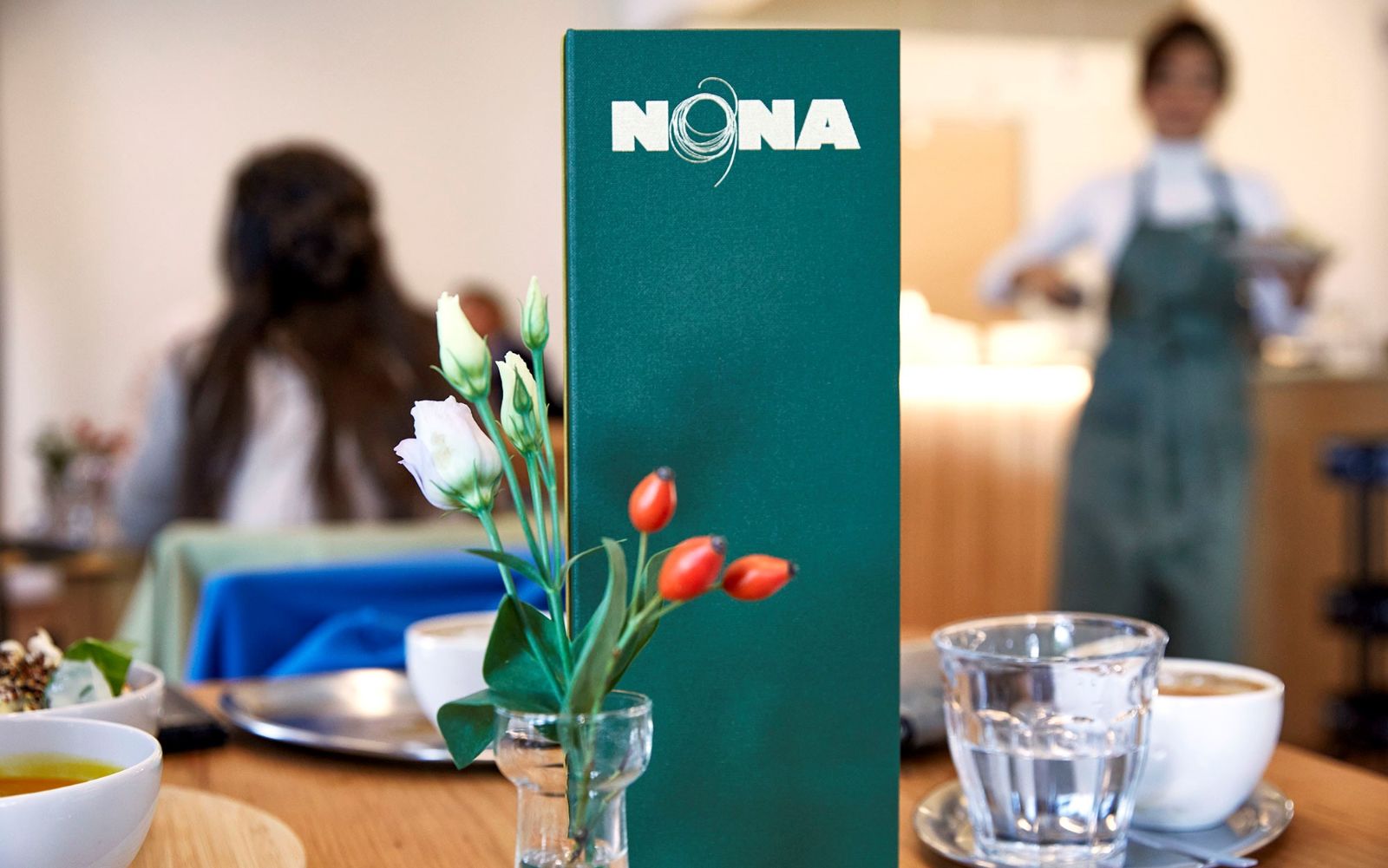 Unsere Menükarte steht im Fokus, Blümchen dekorieren den Tisch.