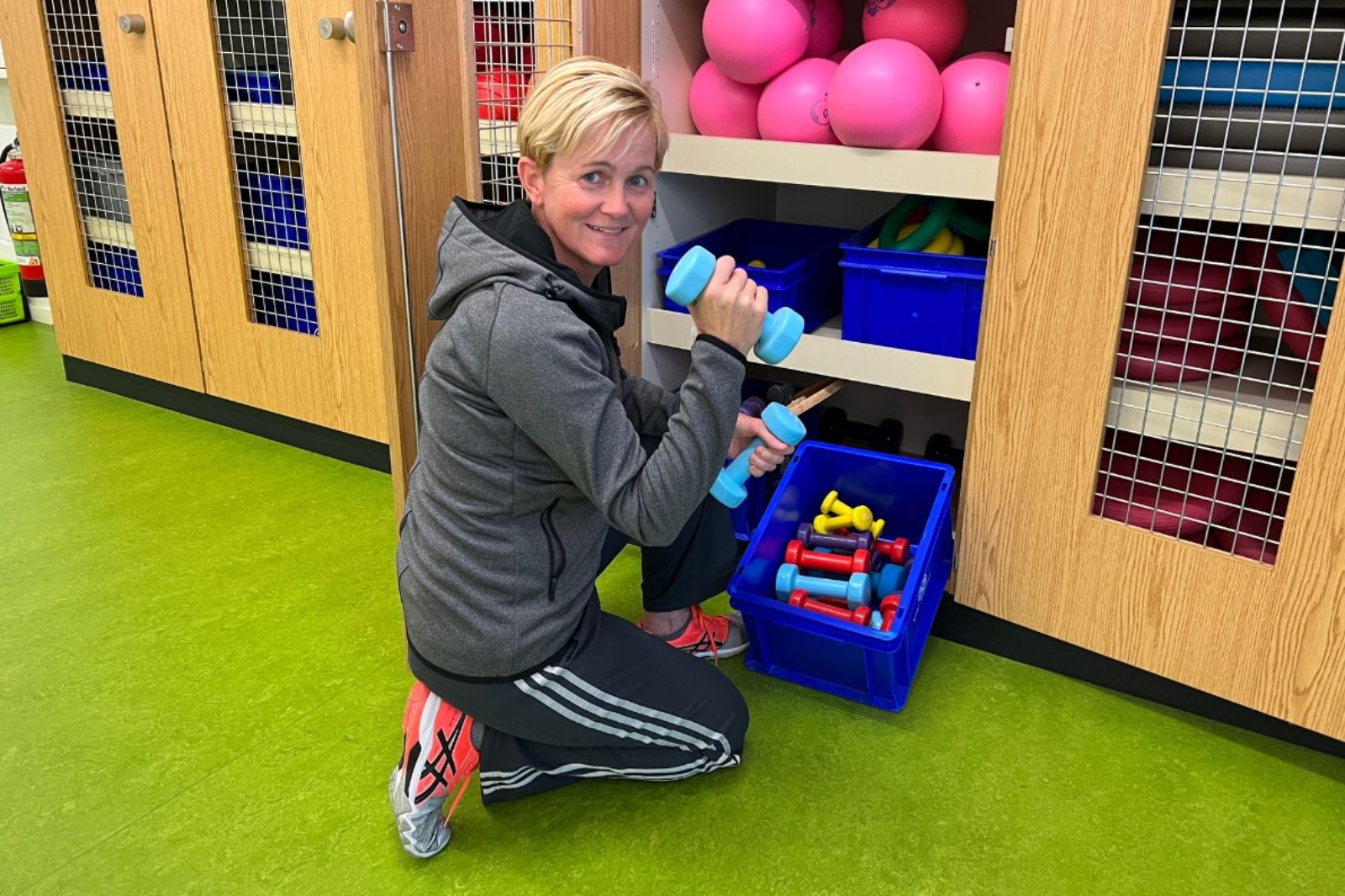 Katrin räumt den Schrank mit Sportzubehör ein.