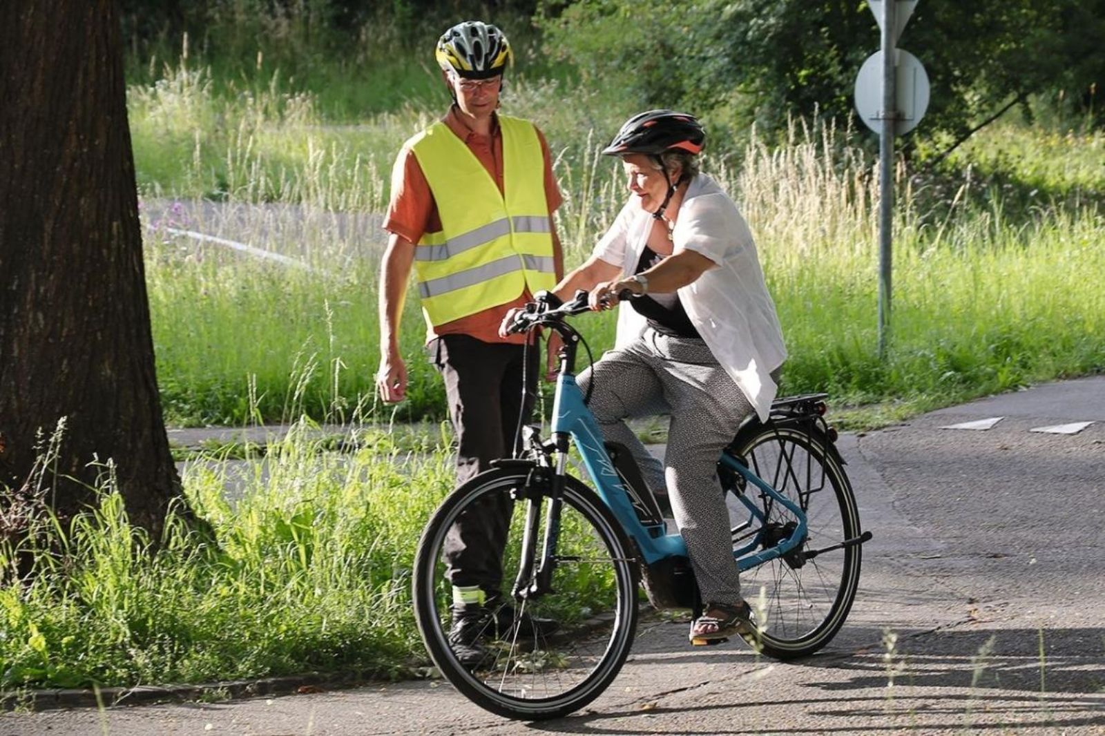 Eine Teilnehmerin an einem E-Bike-Ausflug wird vom Kursleiter unterstützt.